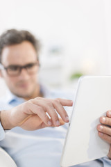 handsome man using a digital tablet, focus on his hand at foregr