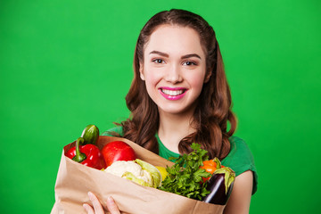 beautiful smiling woman holding a grocery bag full of fresh and