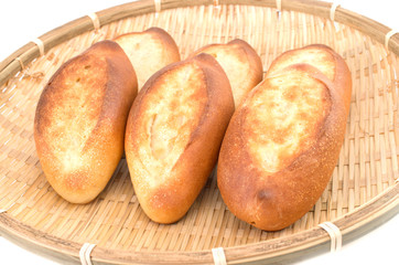 Mini french baguettes in a bamboo plate on white background