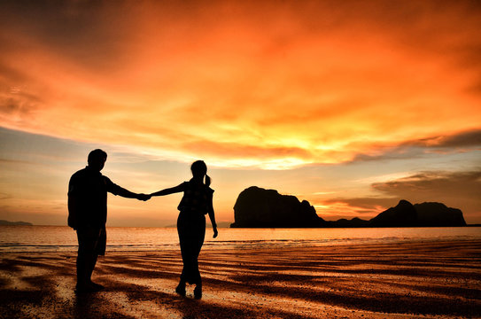 Romantic couple holding hands at sunset on beach