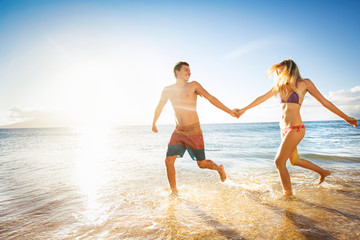 Happy couple running on a tropical beach