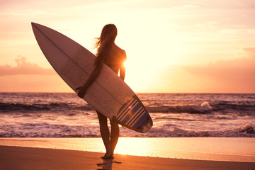 Silhouette surfer girl on the beach at sunset - obrazy, fototapety, plakaty