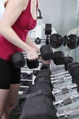 Fototapeta na wymiar Junge Frau trainiert im Fitnessstudio mit Hanteln