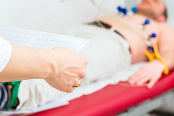 Doktor kontrolliert Patient EKG in Arztpraxis
