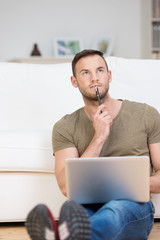nachdenklicher mann mit laptop in der wohnung