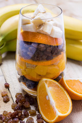 Glass of mixed fresh fruits and raisins with the wholes bananas