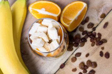Glass of mixed fresh fruits and raisins with the wholes bananas