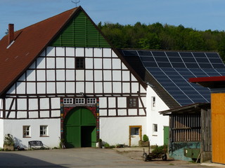 Tradition und Moderne auf einem alten Bauernhof mit Fachwerk und Photovoltaik im Sonnenschein in...