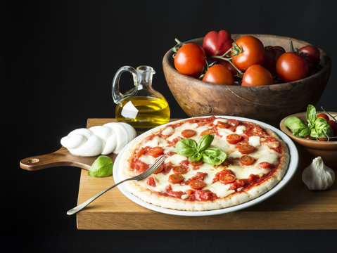 Pizza with ingredients on the wooden table