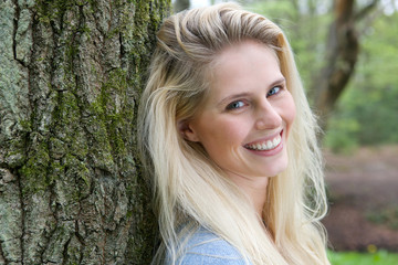 Naklejka premium Beautiful blond woman smiling in the forest
