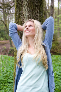 Beautiful young woman leaning on tree