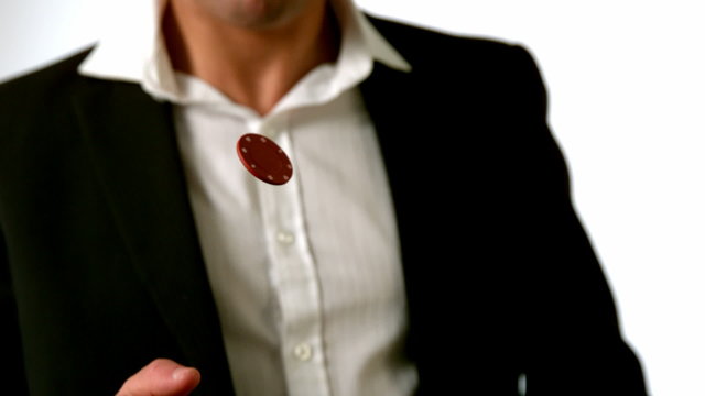 Man in suit flipping red casino chip