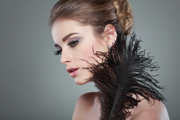 portrait of sexy whiteheaded young woman with black feat on grey