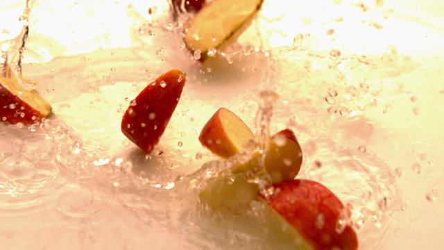 Apple pieces falling and bouncing on white wet surface