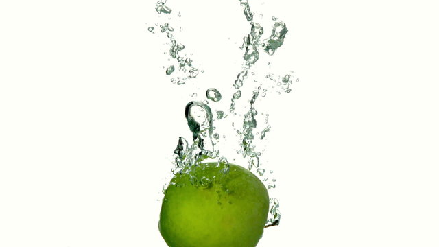 Green apple plunging into water on white background