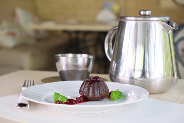 a served table with a muffin, a coffee pot and a cup