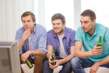 happy male friends with beer watching tv at home