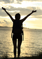 Fototapeta premium cheering woman hiker open arms at sunrise seaside