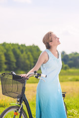 Obraz premium Young Caucasian Blond Laughing Outdoors Standing Near Her Bicycl