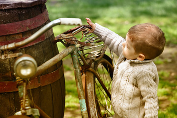 2 years old curious Baby boy walking around the old bike
