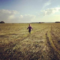 Muurstickers girl running through summer field © romantsubin