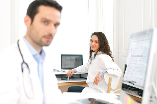 Doctor working at the office with nurse in background