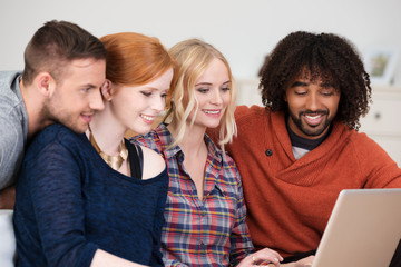 lachende freunde schauen zusammen auf laptop