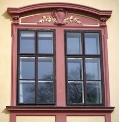 Ornamented old red wooden window on facade