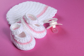 Baby girl booties and bonnet on pink background