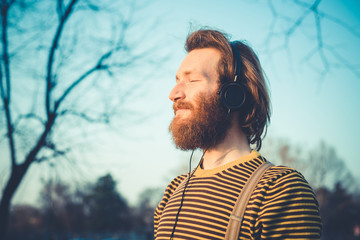 young bearded stylish handsome hipster man listening music