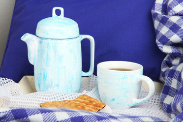 Cup and teapot with cookies on bed close up