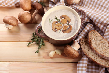 Fototapeta na wymiar Mushroom soup in pot, on napkin, on wooden background