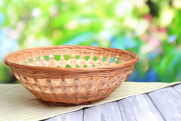 Fototapeta na wymiar Empty wicker basket on wooden table, on bright background