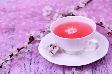 Fragrant tea with flowering branches on wooden table close-up