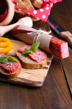 Composition with knife,  tasty sandwiches with salami sausage,