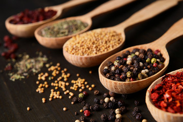 Different spices in spoons on wooden background