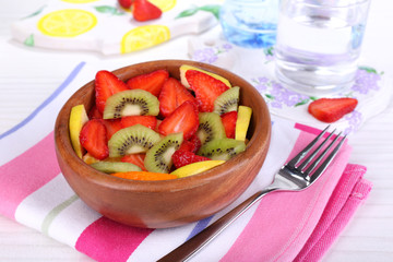 Various sliced fruits in bowl on table close-up