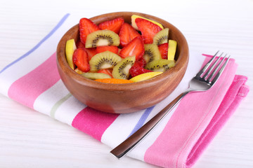 Various sliced fruits in bowl on table close-up