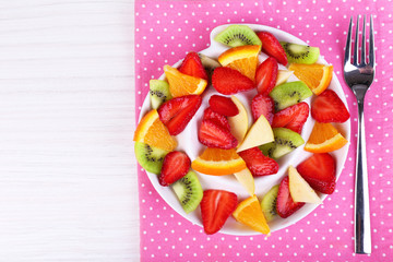 Various sliced fruits on plate on table close-up