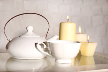 Composition with tea in cup and teapot and candles