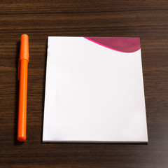 Orange pen and note paper on a wood table