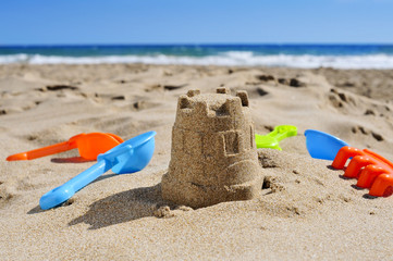 sandcastle and toy shovels on the sand of a beach