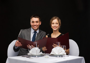 smiling couple with menus at restaurant