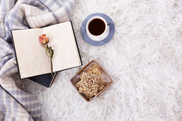 Composition with warm plaid, book, cup of hot drink