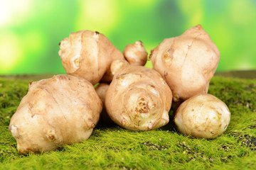 Topinambur roots on grass on bright background