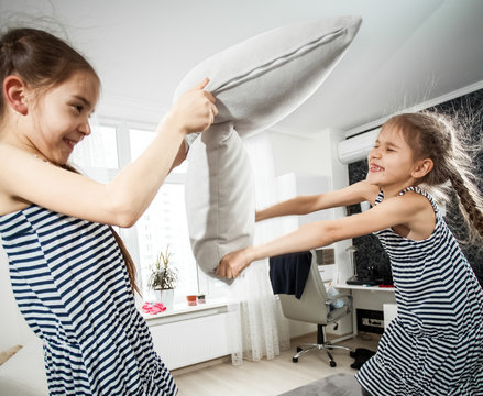 Portrait Of Two Little Sisters Fighting With Pillows