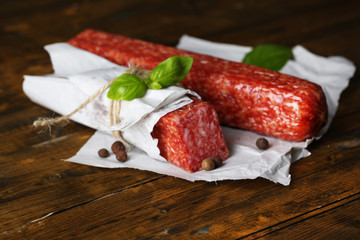 Tasty salami sausage and spices on wooden background
