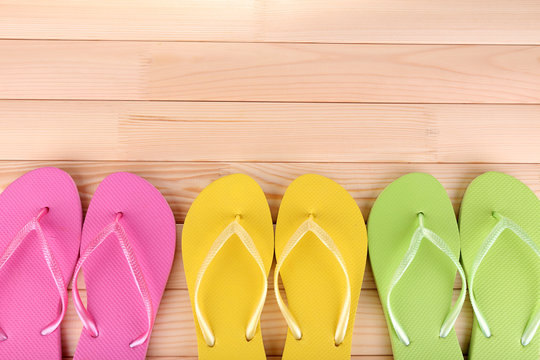 Bright flip-flops on wooden background