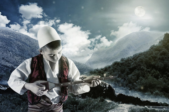 unge in Volkstracht spielt bei Nacht Instrument
