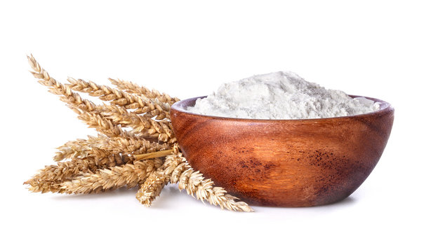 flour with wheat in a wooden bowl on a white background